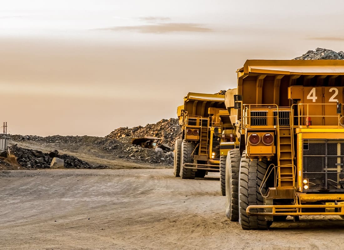 Mining Insurance - Mining Dump Trucks Transporting Coal for Processing From a Large Mine at Dusk