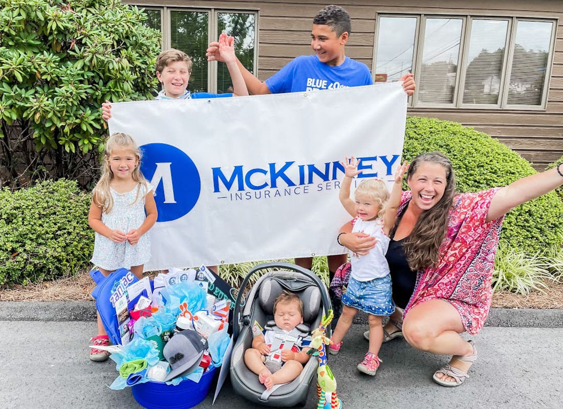 Our Community Partners - Closeup View of a Cheerful Family with Kids Receiving a Community Giveaway Prize from McKinney Insurance Services