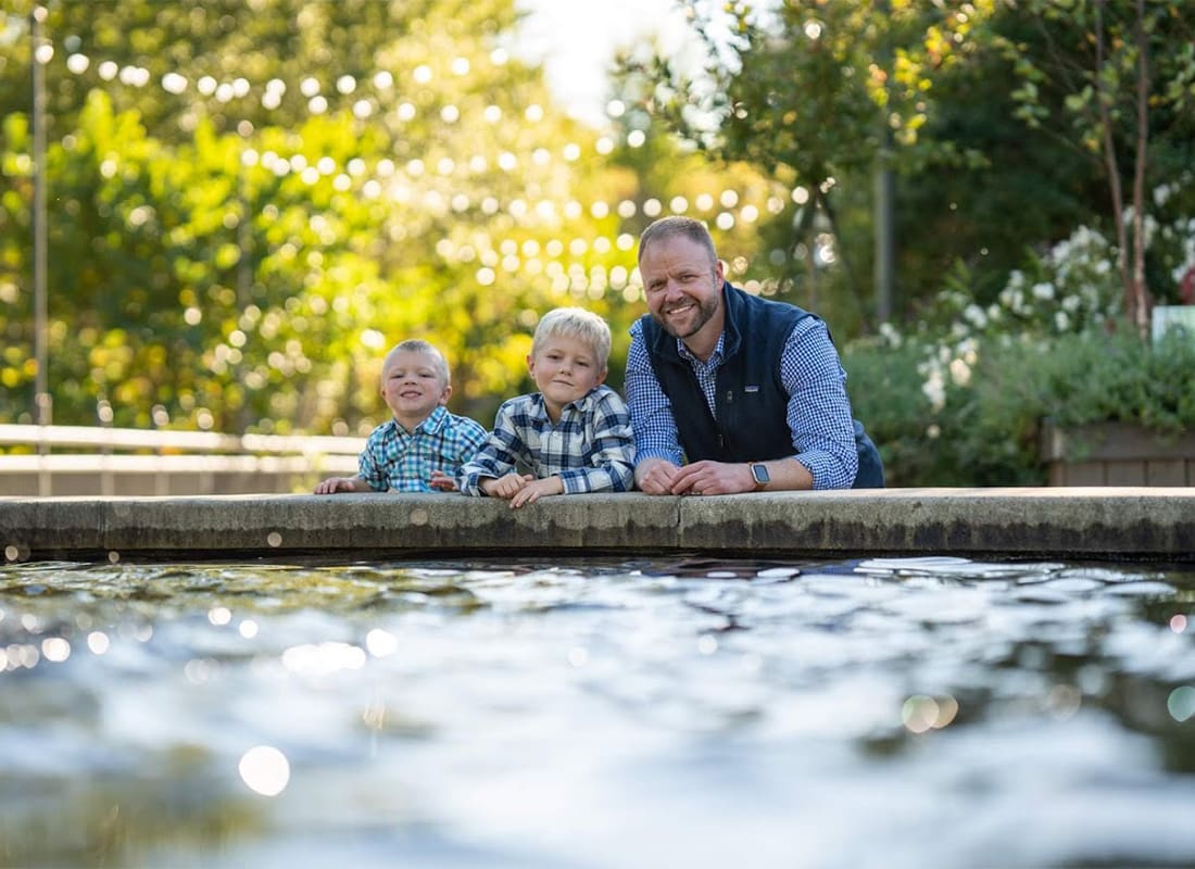 We Are Independent - Portrait of Chad McKinney with his Two Sons Next to a Fountain in the Park on a Sunny Day